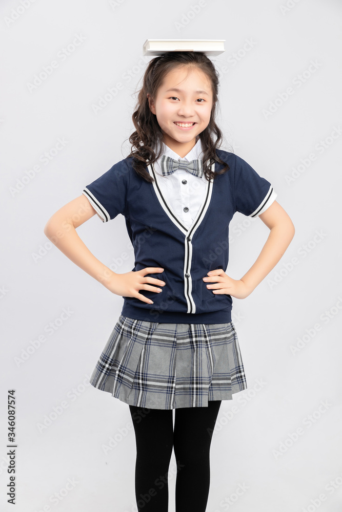 Asian primary  school girls in school uniforms on a gray background