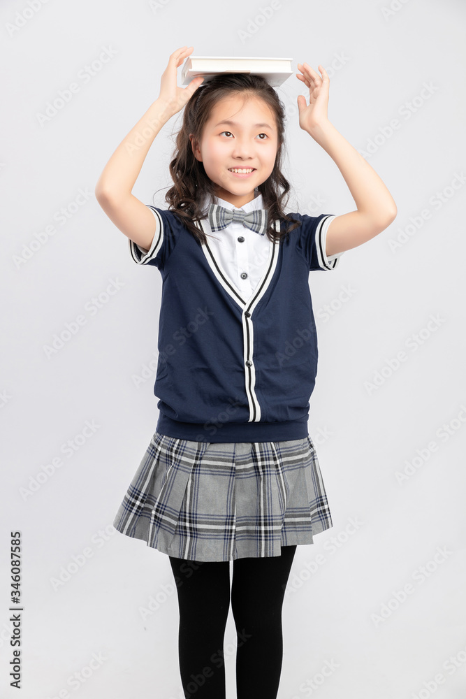 Asian primary  school girls in school uniforms on a gray background