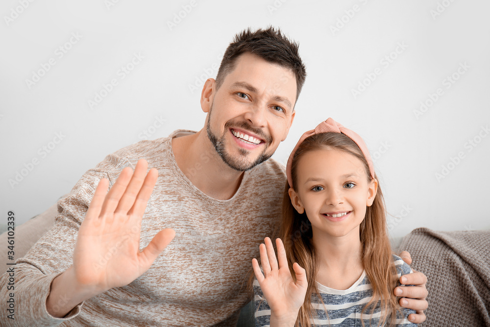 Father with little daughter video chatting at home