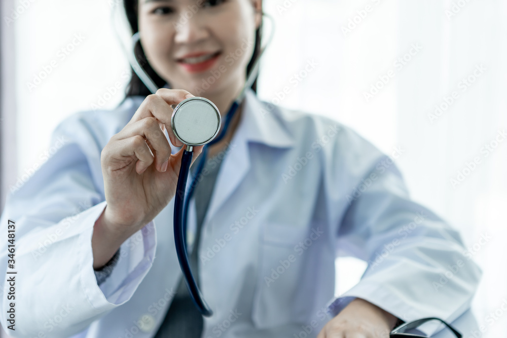 Medical concept of Asian female doctor in white coat with stethoscope working in office in hospital.