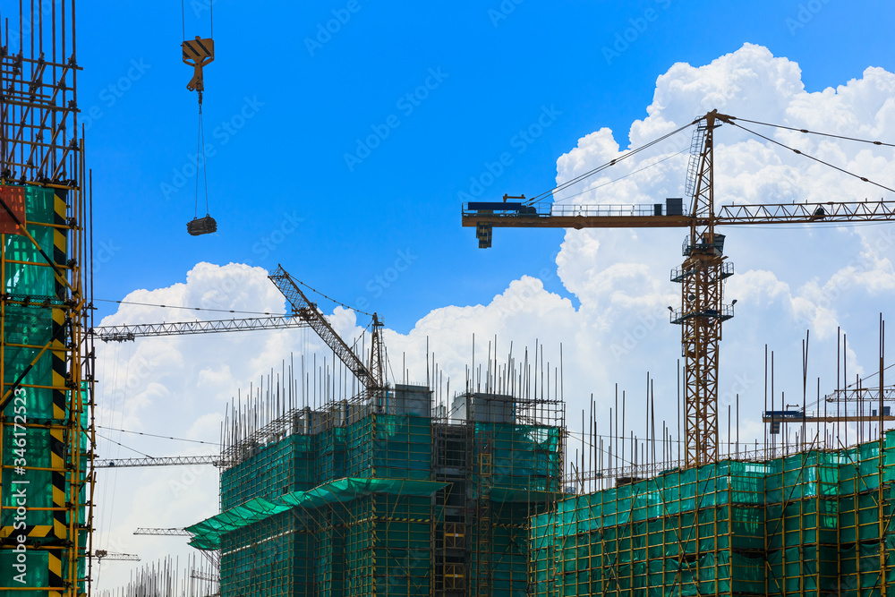 Crane and building construction site against blue sky.