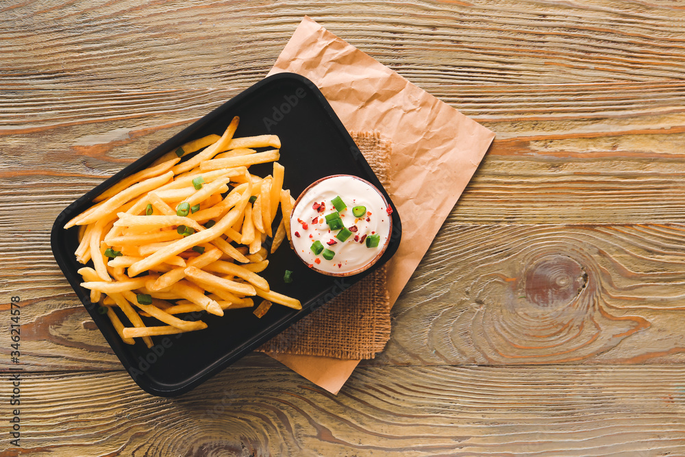 Plate with tasty sour cream and french fries on table