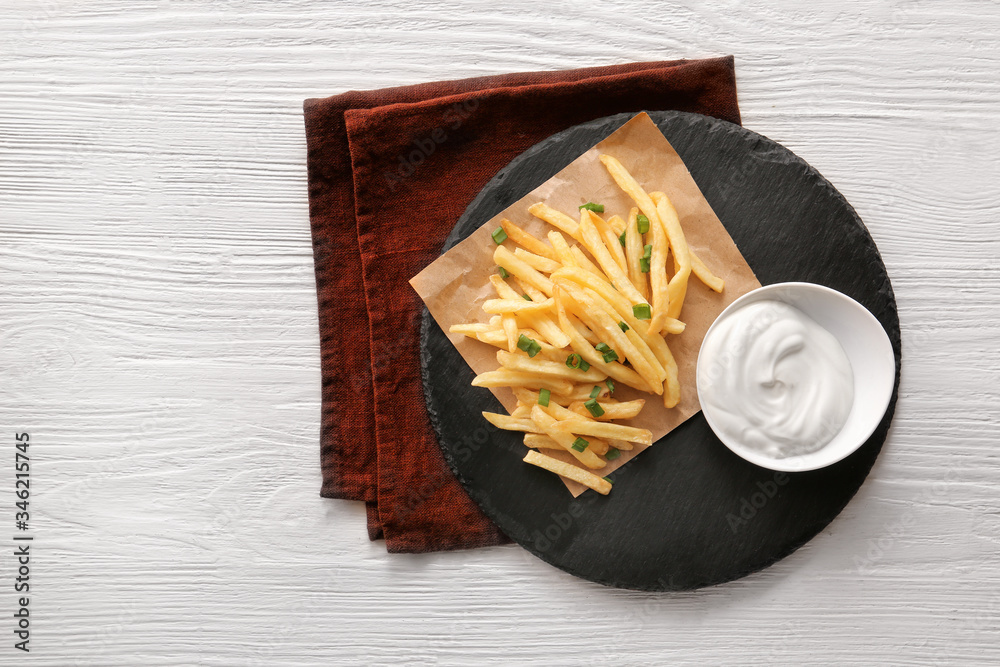 Tasty sour cream and french fries on table