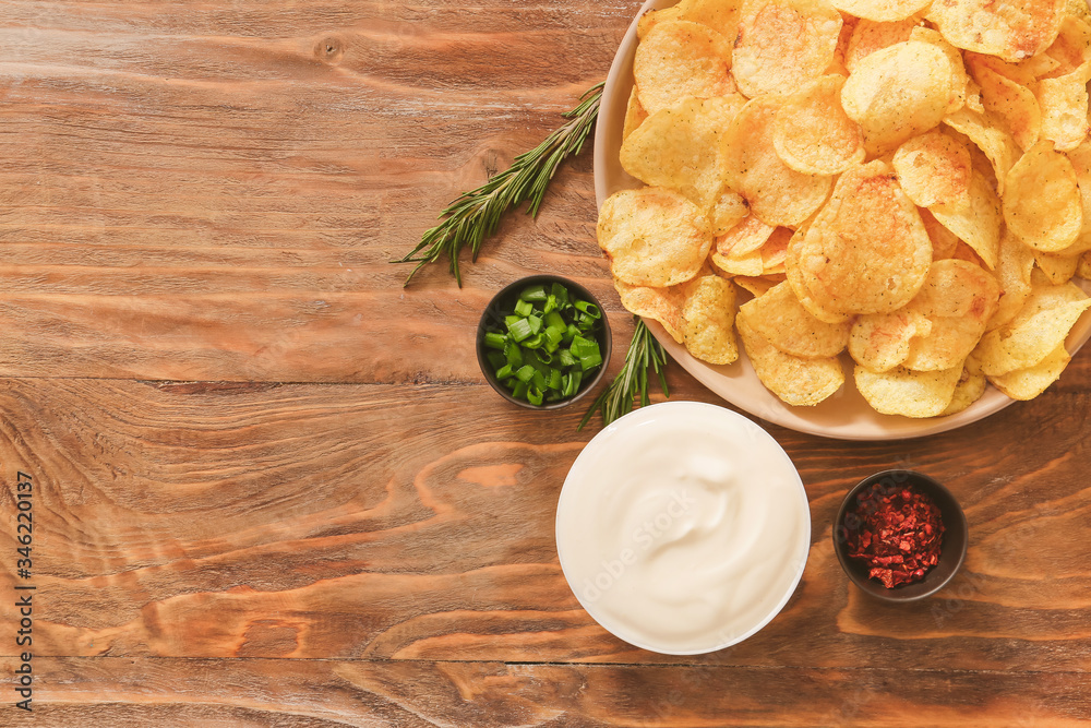 Bowl with tasty sour cream and potato chips on table