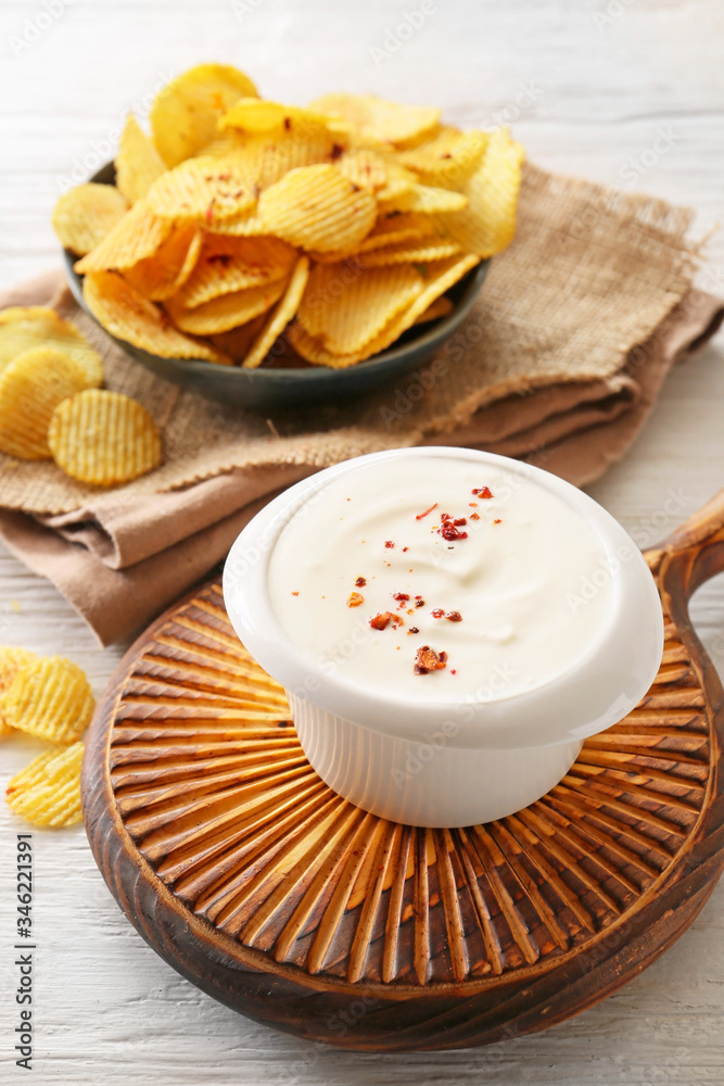 Bowl with tasty sour cream and potato chips on table