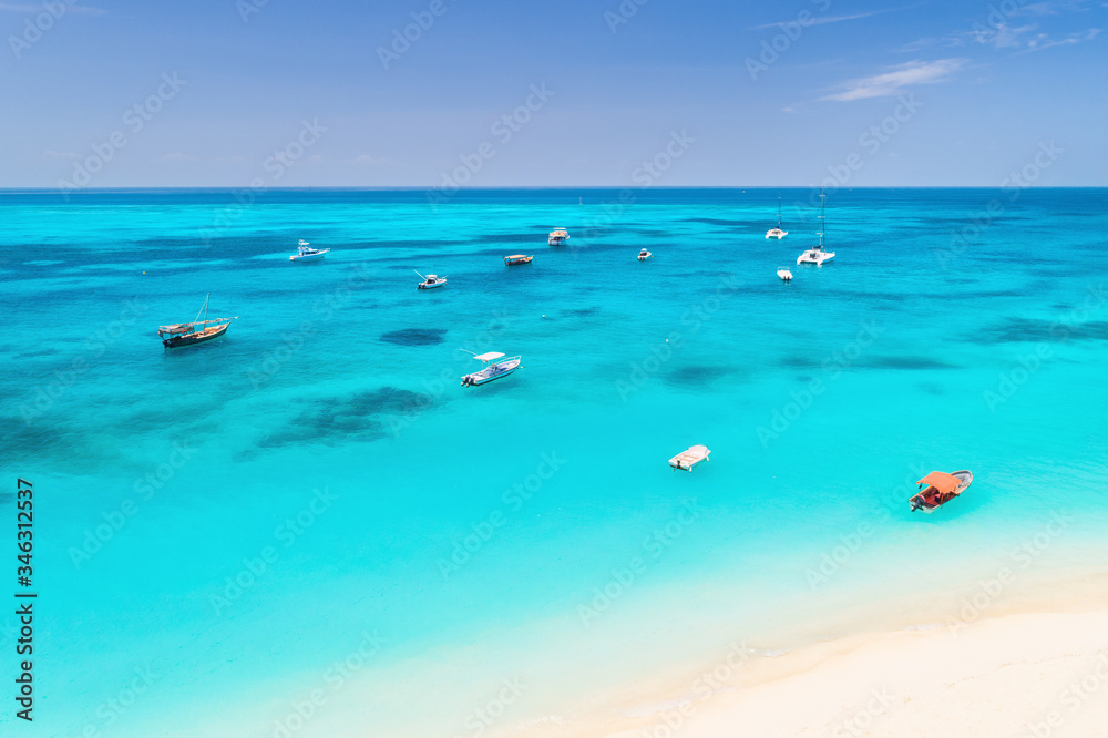 Aerial view of the fishing boats on tropical sea coast with white sandy beach at sunset. Summer trav