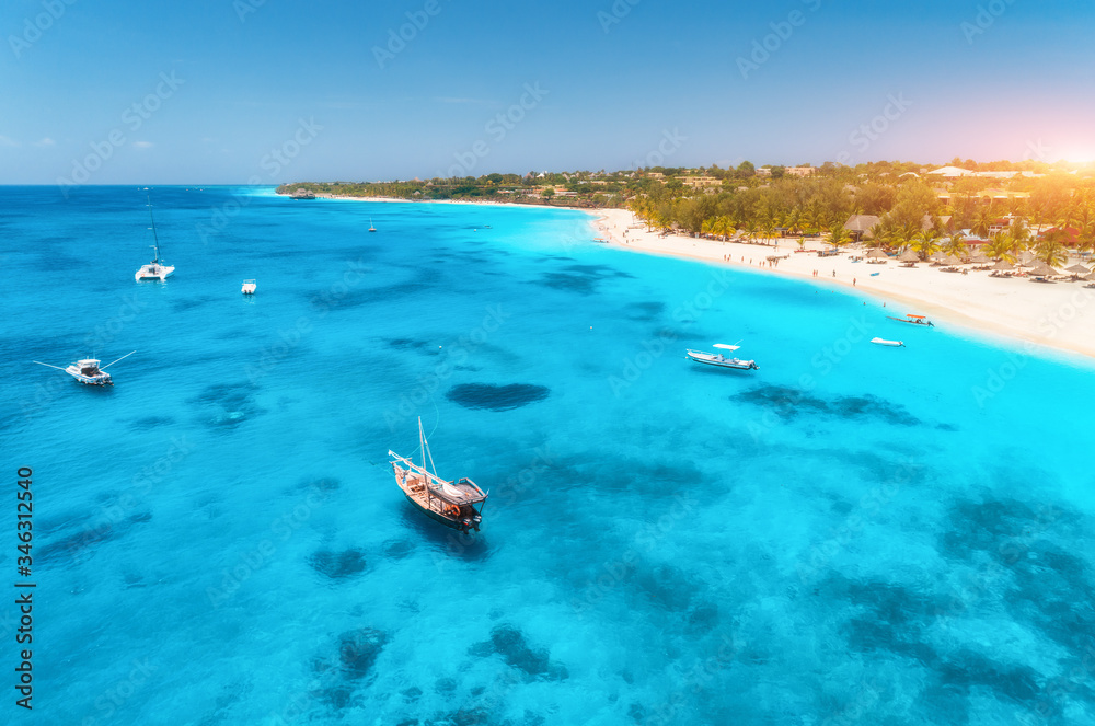 Aerial view of the fishing boats on tropical sea coast with sandy beach at sunrise. Summer holiday i