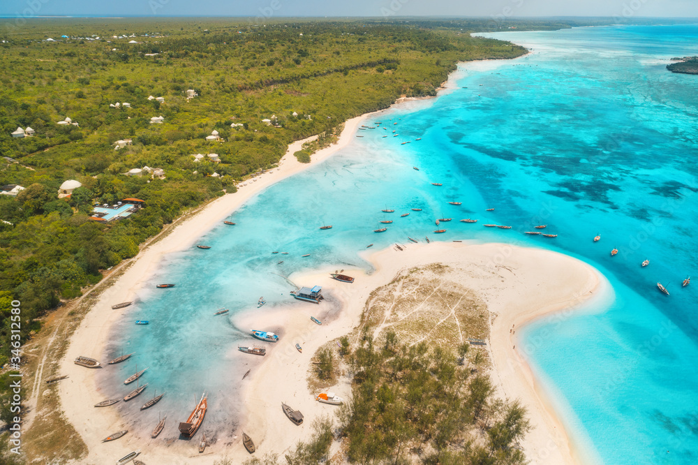 Aerial view of the fishing boats on tropical sea coast with sandy beach at sunset. Summer travel in 