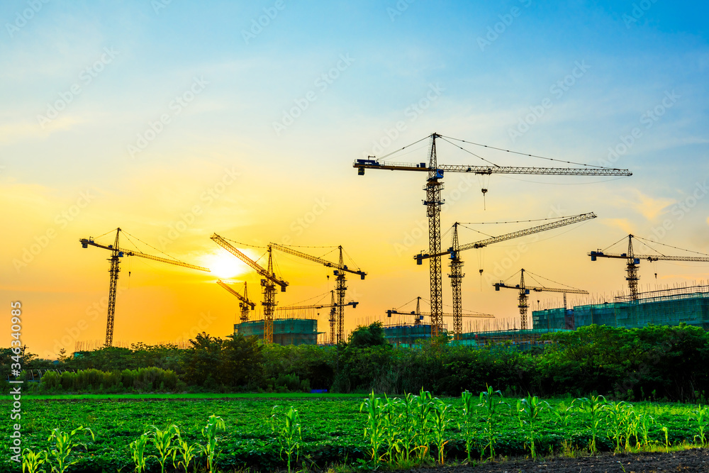 Tower crane and building construction site silhouette at sunrise.