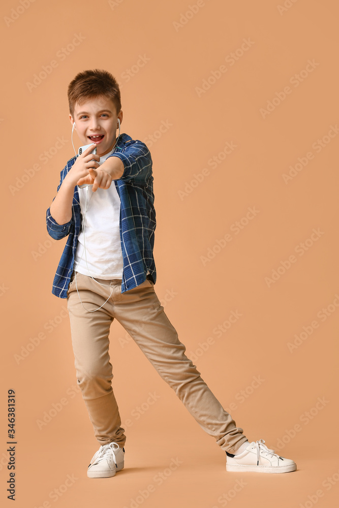 Cute little boy listening to music against color background