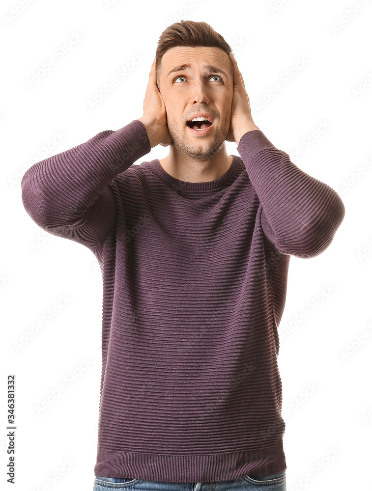 Young man suffering from loud noise on white background