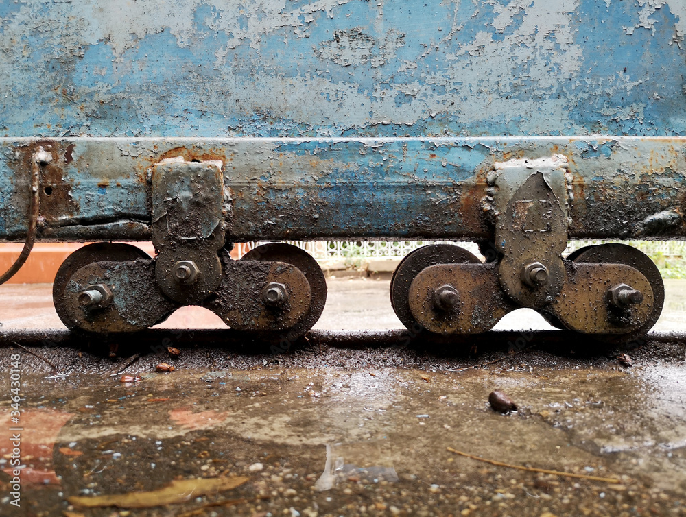 The castors of the old blue iron doors are rusted in wet and dirty floor