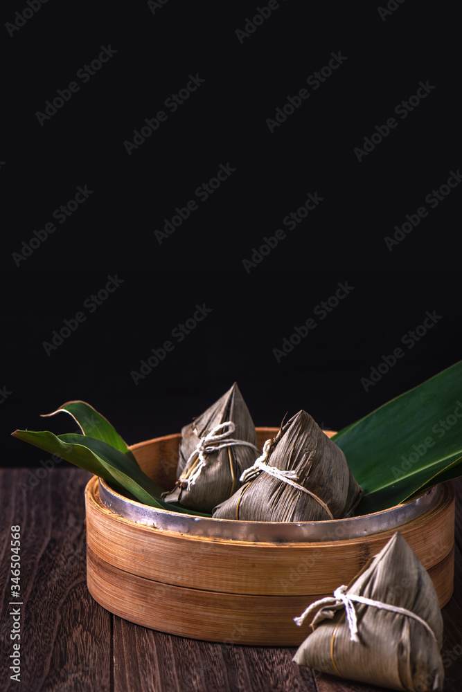 Zongzi - Chinese rice dumpling zongzi in a steamer on wooden table black retro background for Dragon