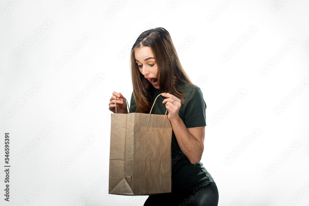 Young woman with brown paper bag. Emotion of surprise. Taking gift. Celebration concept.