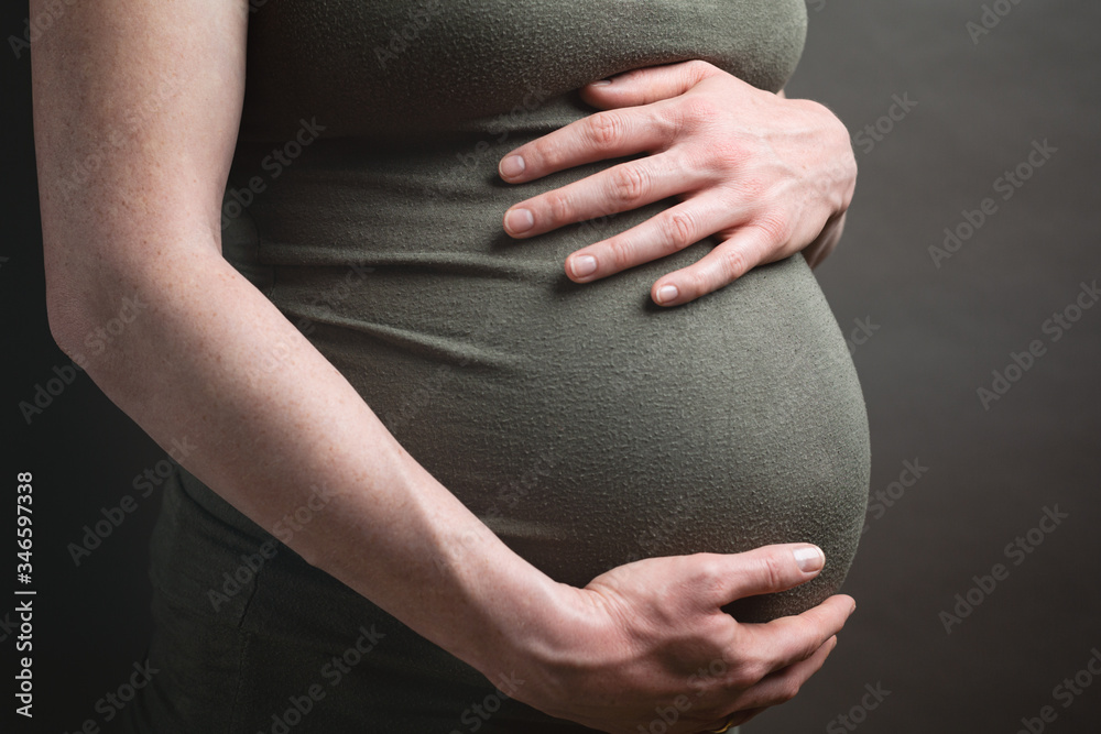 Pregnant Woman Holding Her Belly, Studio Portrait