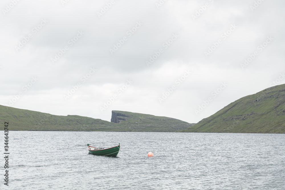 Morning view on lonely boat on cloudy Sorvagsvatn lake on cliffs of Vagar island, Faroe Islands, Den