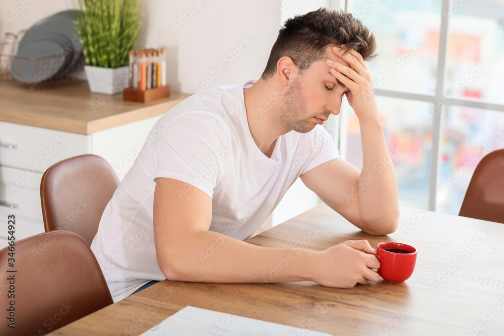 Sleepy man drinking coffee in kitchen