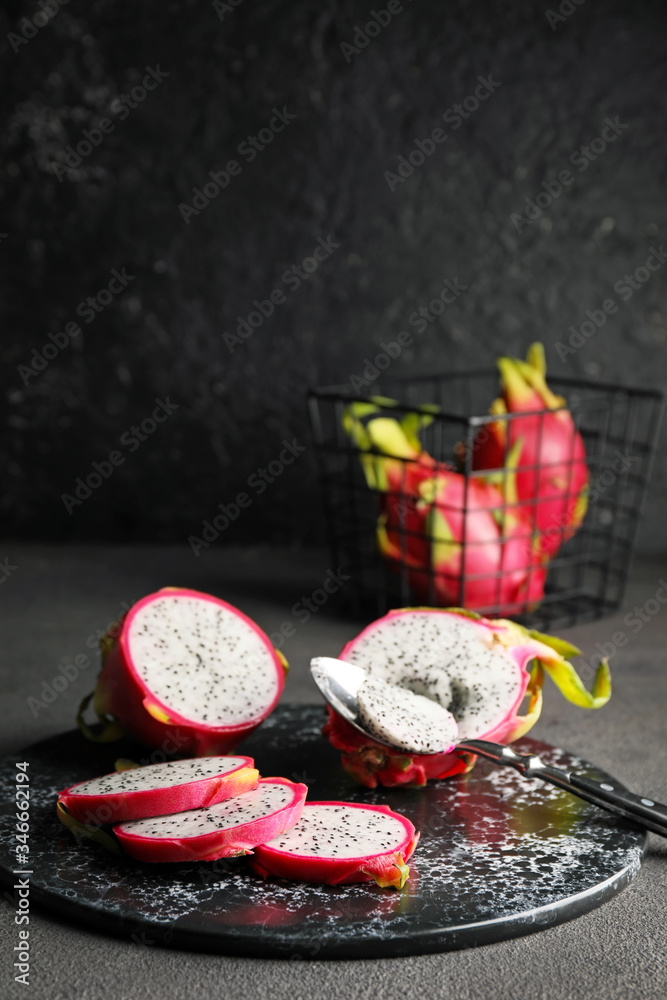 Board with tasty dragon fruit on dark background