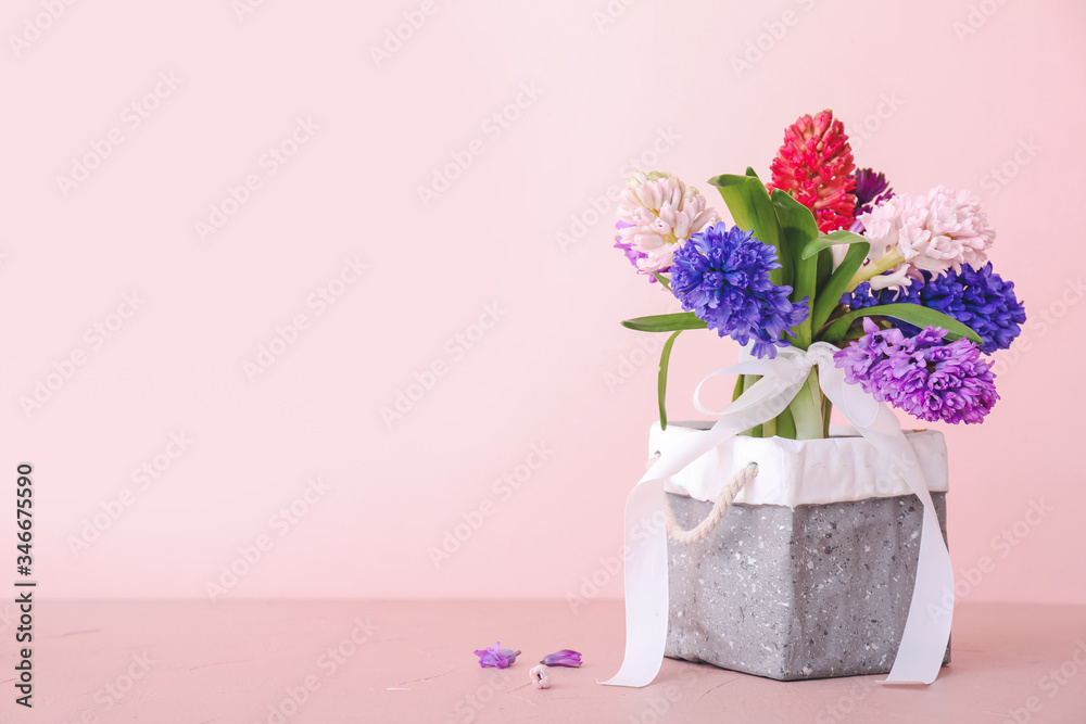 Box with beautiful hyacinth flowers on table against color background