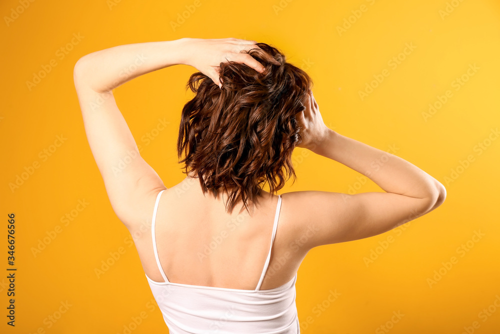 Young woman with beautiful short wavy hair on color background