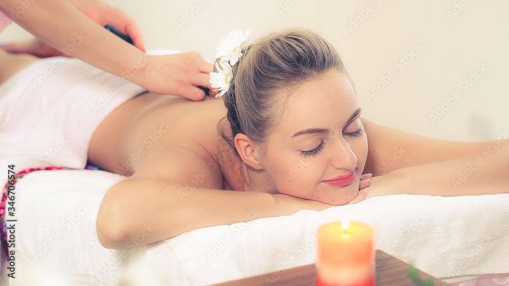 Relaxed woman getting back massage in luxury spa with professional massage therapist. Wellness, heal