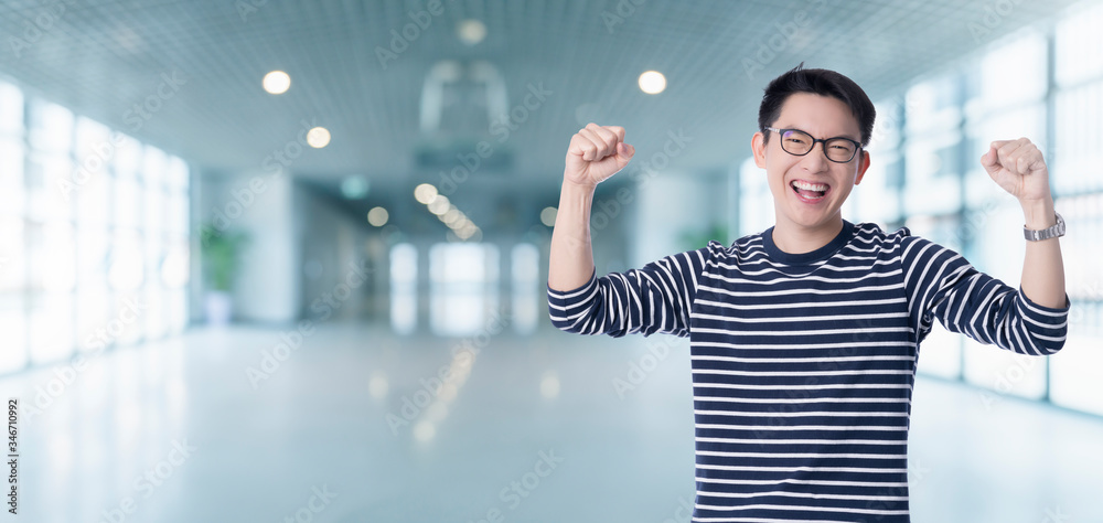 exciting smart casual asian male hand rise big toothy smile with blur office background successful a