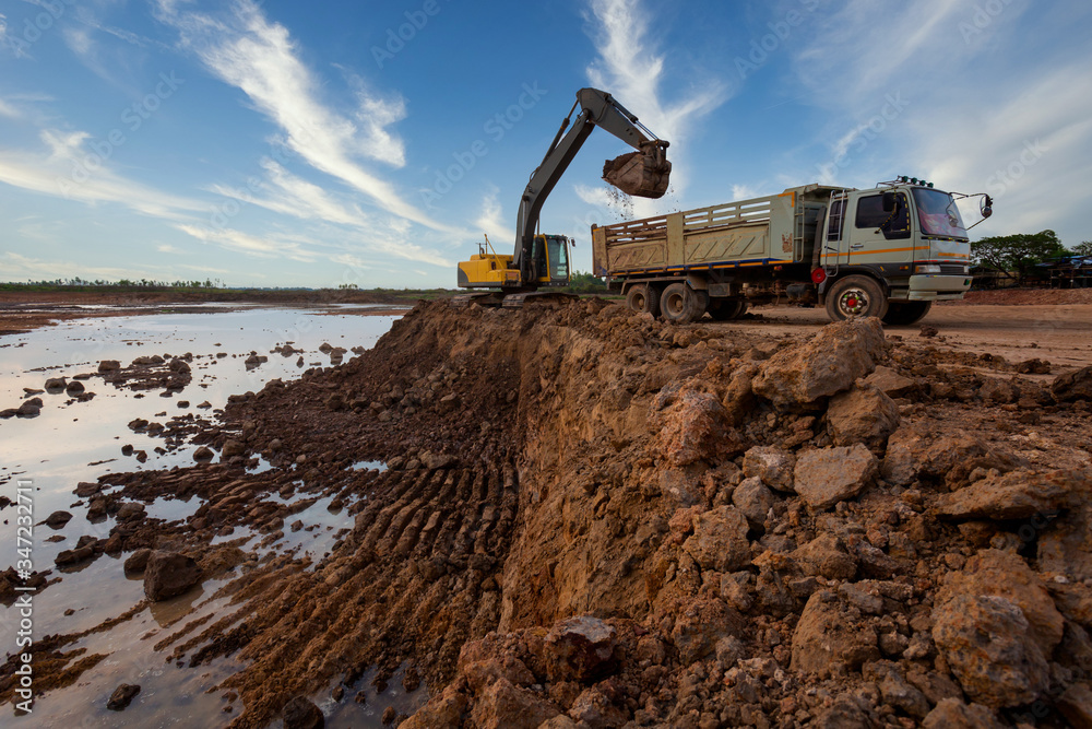 excavator at sandpit during earthmoving works ifilling a dump truck with rock and soil for fill at a