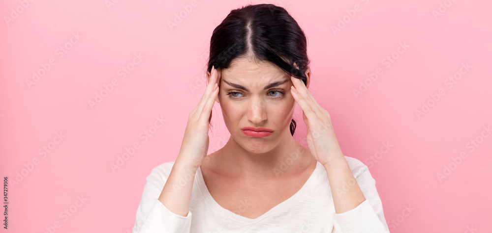 Young woman feeling stressed on a pink background