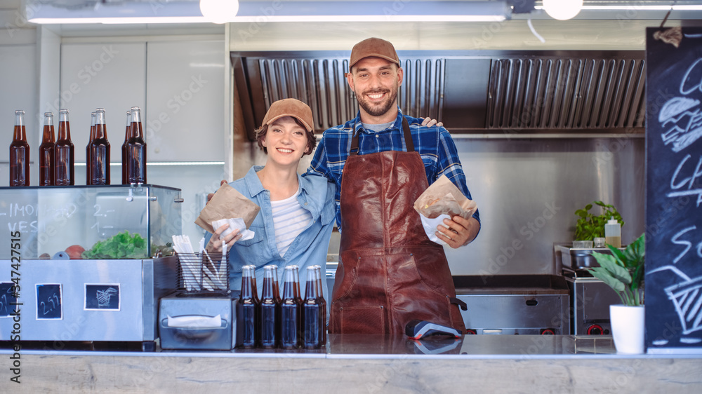 Successful Food Truck Male and Female Employees Pose for the Camera. They Wear Brown Caps. They are 