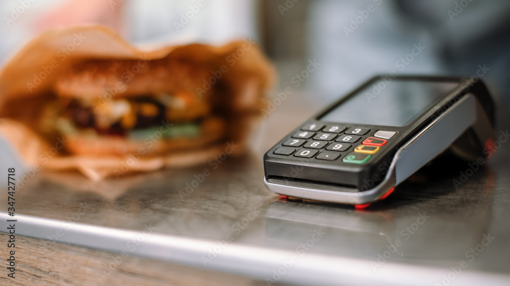 Close Up Shot of a Modern Contactless Payment Terminal with Tasty Burger in the Backgroung. Street F