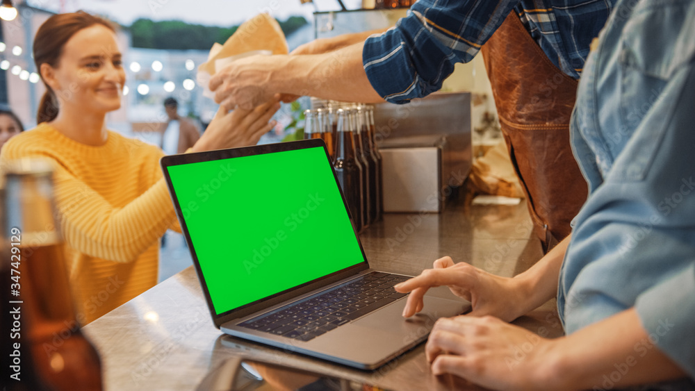 Laptop Computer with Green Screen Mock Up Screen is Placed on a Counter at a Street Food Truck or Ki