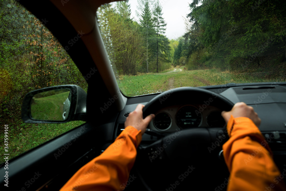 Driver dressed bright orange jacket driving a modern off road left hand drive LHD car on the mountai