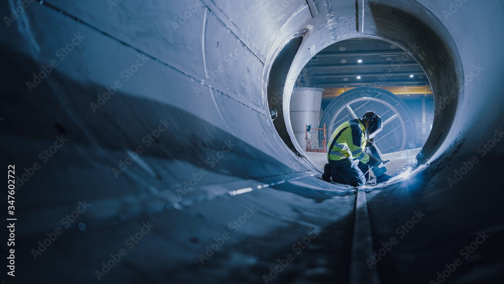 Professional Heavy Industry Welder Working Inside Pipe, Wears Helmet and Starts Welding. Constructio