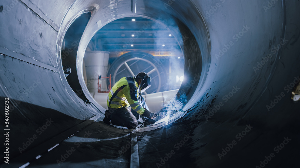 Professional Heavy Industry Welder Working Inside Pipe, Wears Helmet and Starts Welding. Constructio