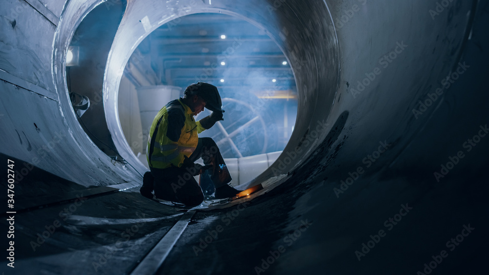 Professional Heavy Industry Welder Working Inside Pipe, Wears Helmet and Starts Welding. Constructio