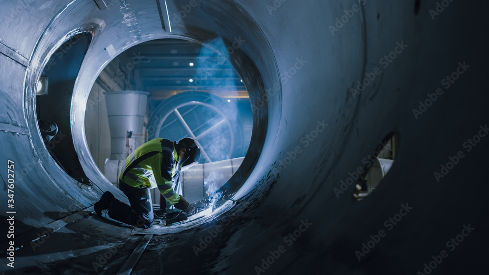 Professional Heavy Industry Welder Working Inside Pipe, Wears Helmet and Starts Welding. Constructio