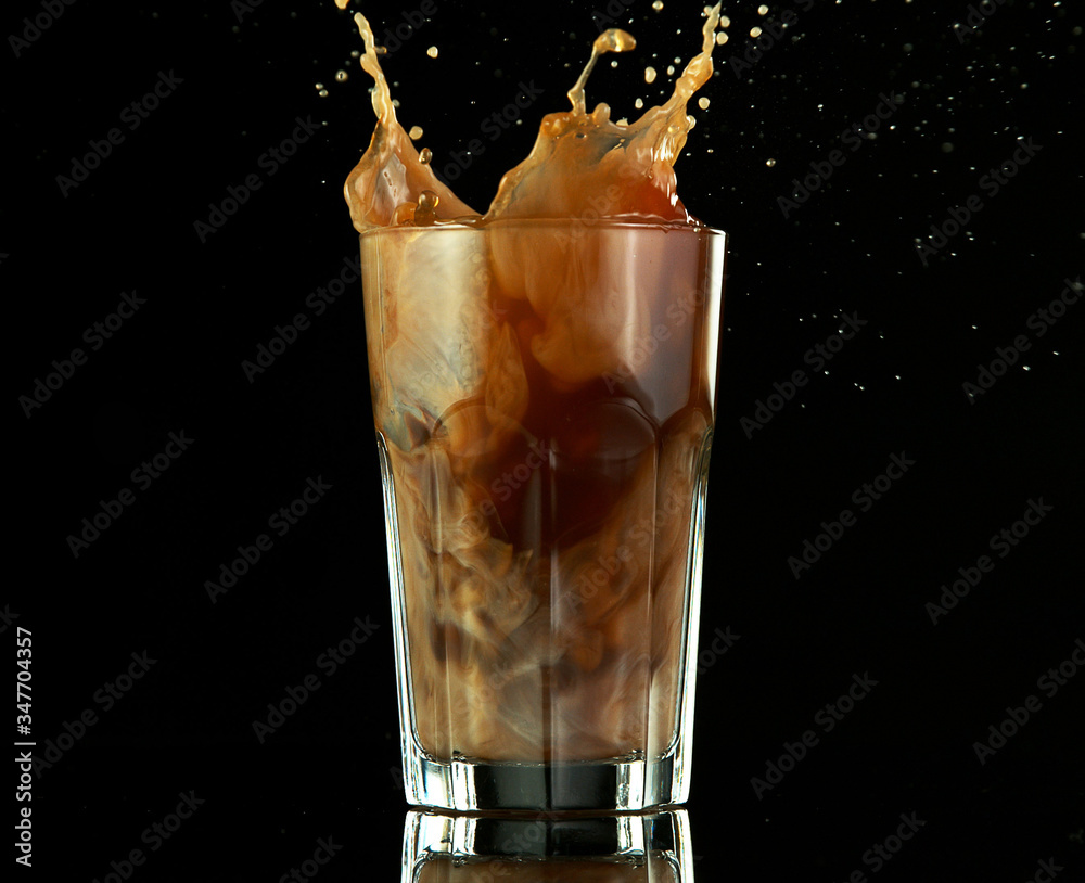 Splashing ice coffee drink on black background