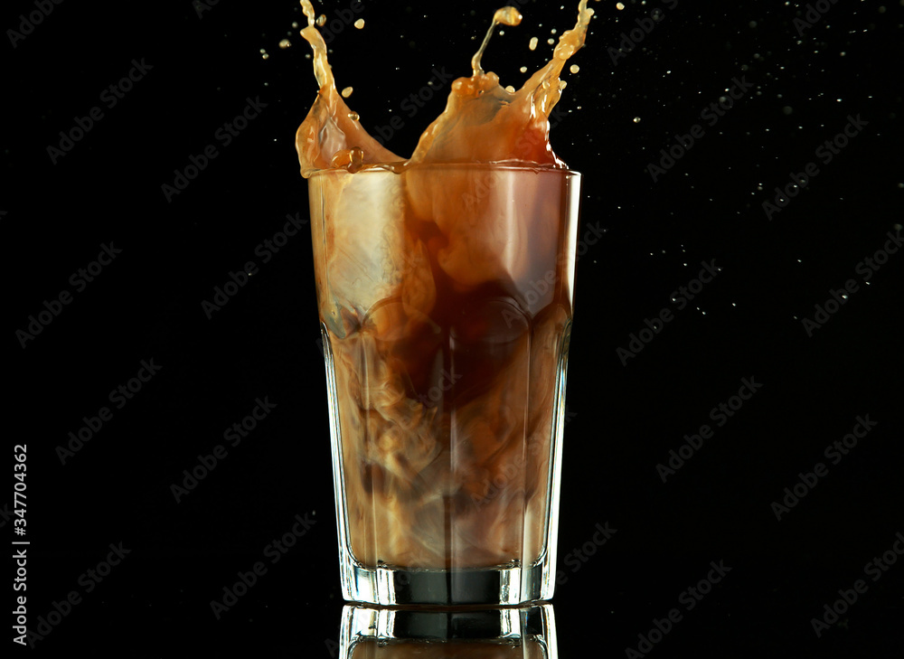 Splashing ice coffee drink on black background