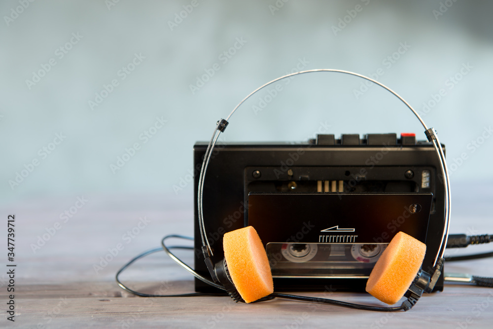 Old portable cassette player and headphones on a abstract background. Vintage advertisement style