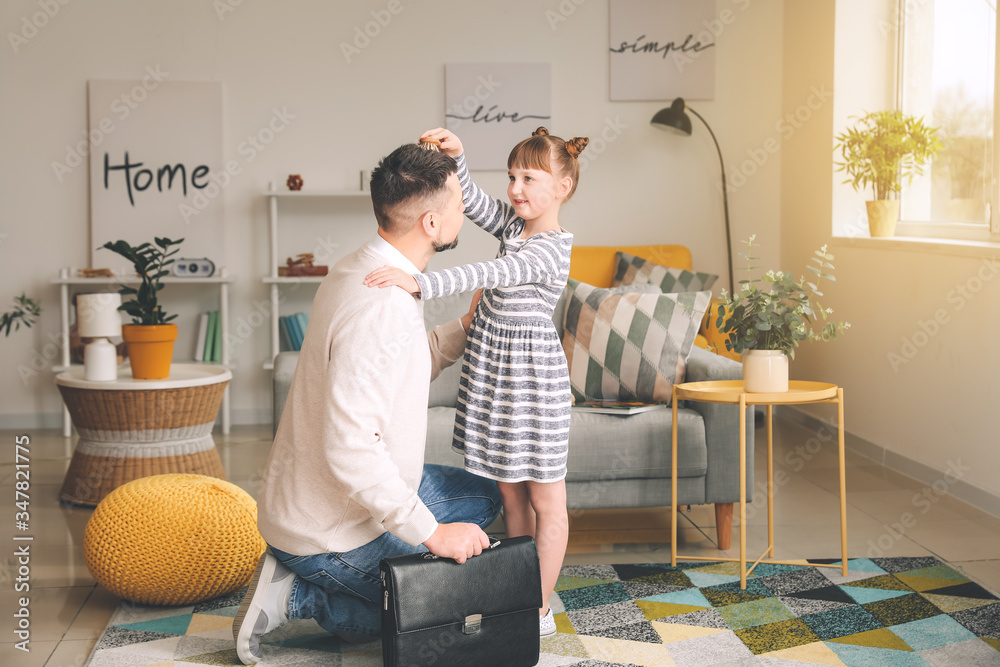 Little daughter brushing hair of her father before work at home in morning