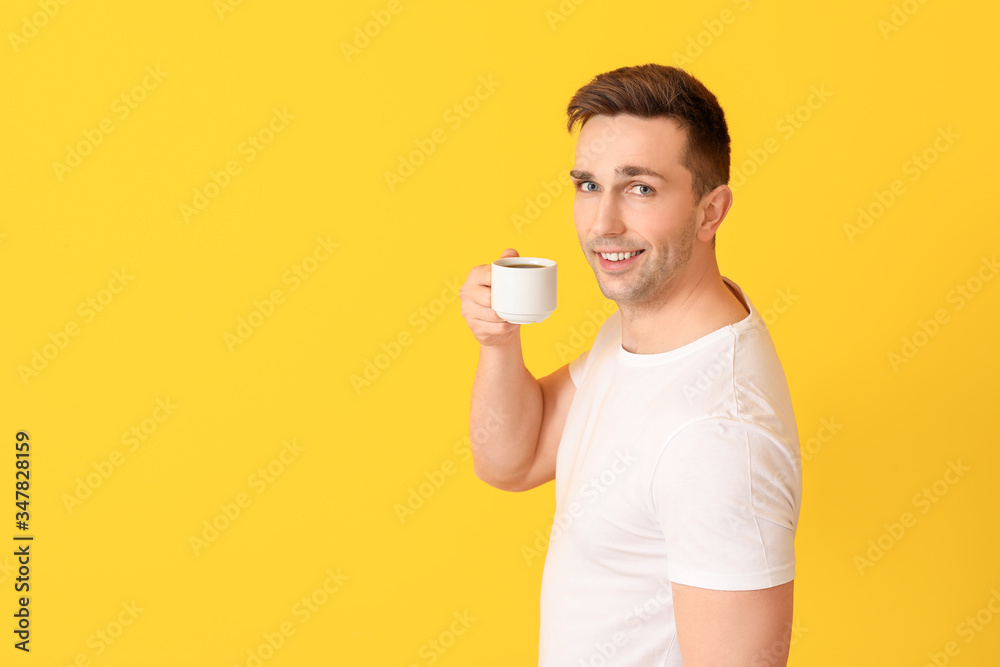 Handsome man with coffee on color background