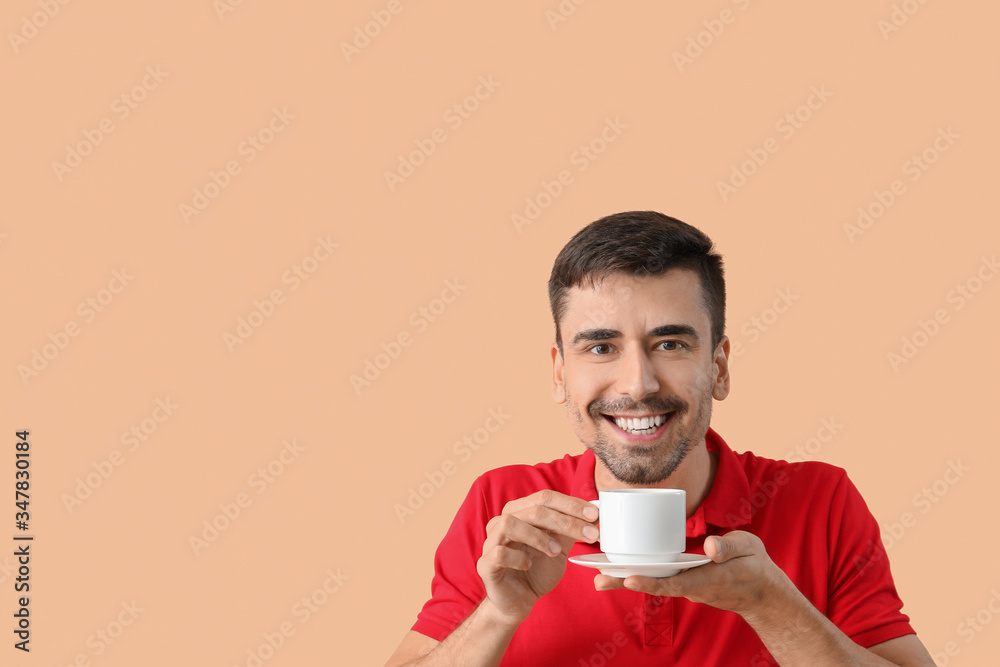 Young man with cup of hot coffee on color background