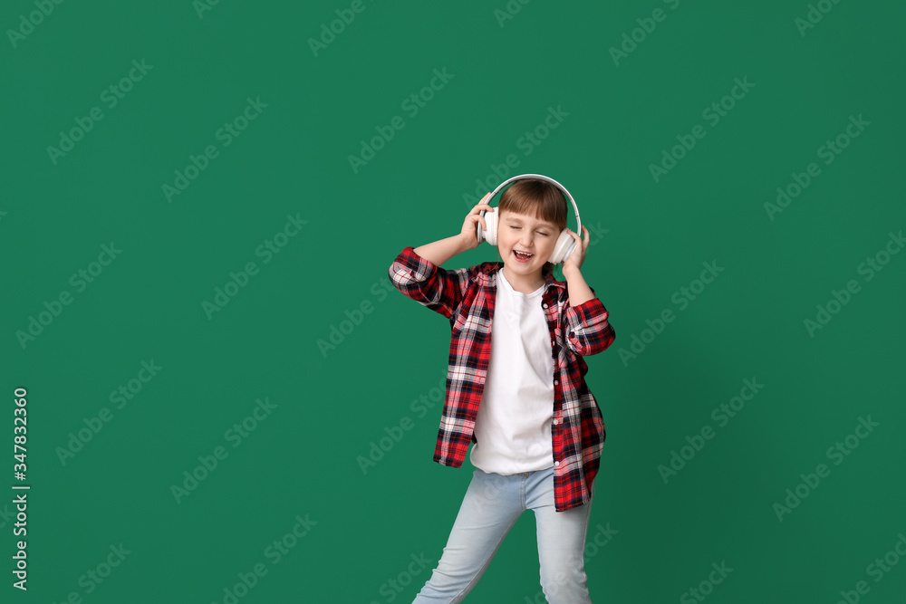 Cute little girl dancing and listening to music against color background