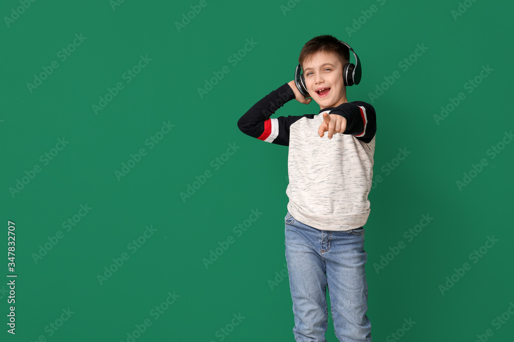 Cute little boy listening to music against color background