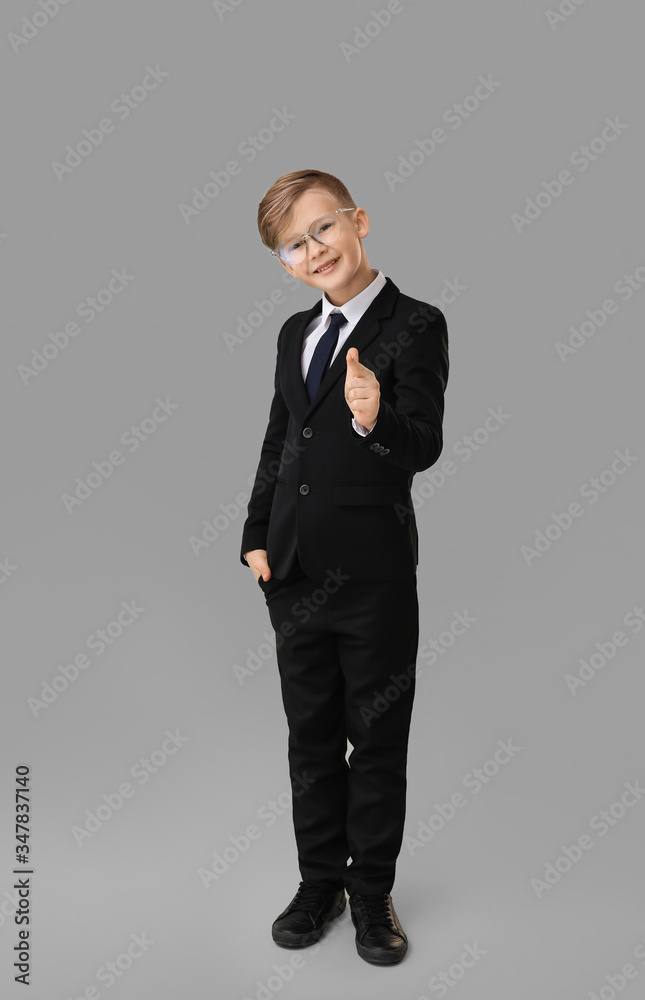 Portrait of little secretary pointing at viewer on grey background