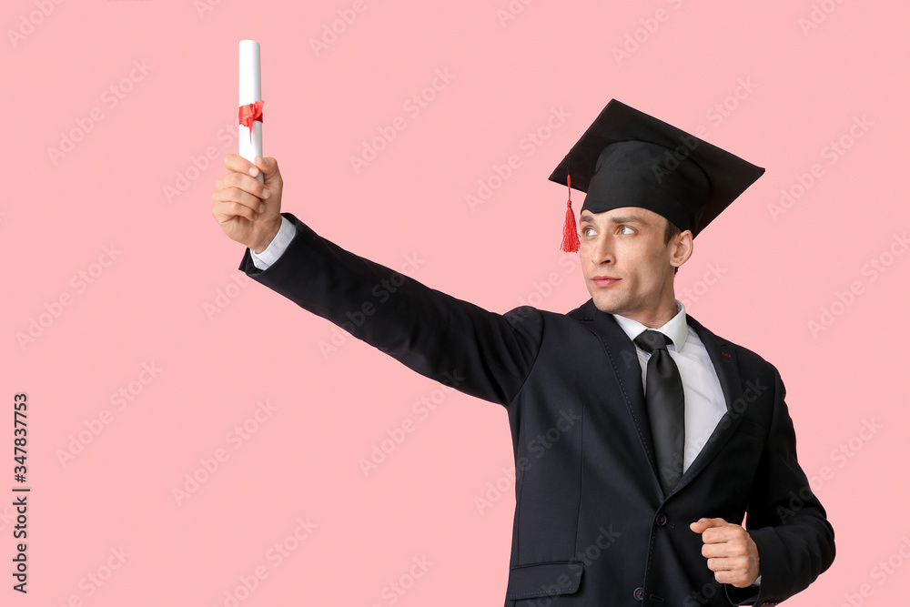 Young man in graduation hat and with diploma on color background