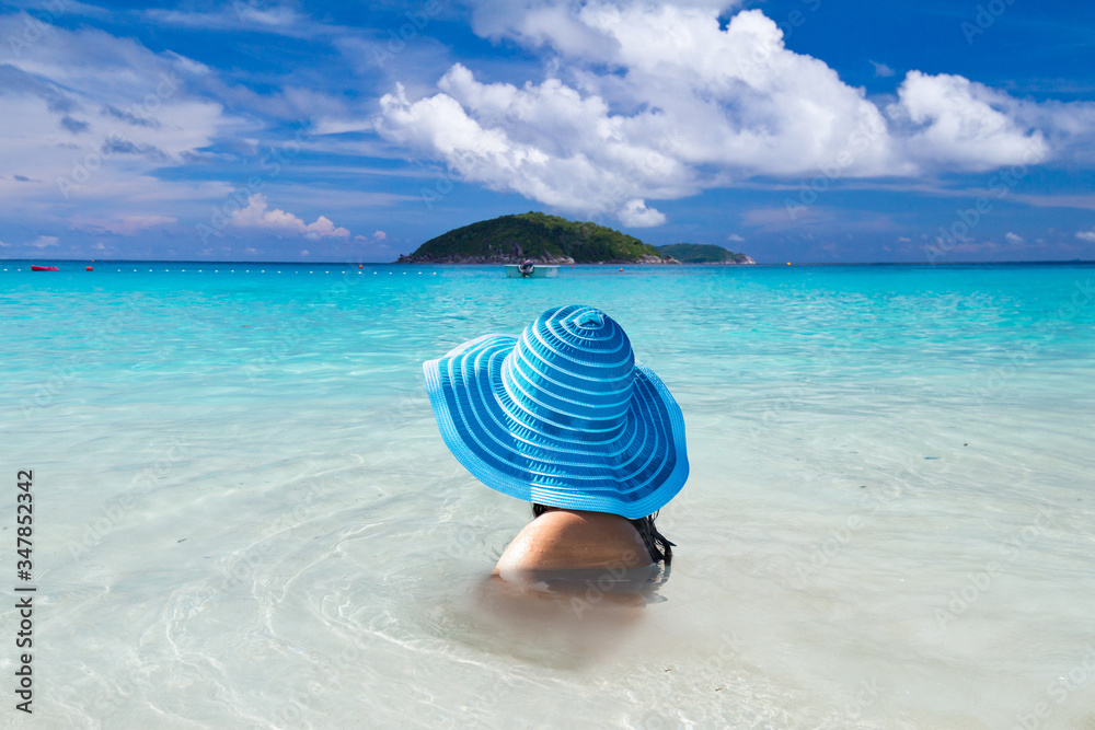 Woman in hat in the water of tropical beach, Thailand