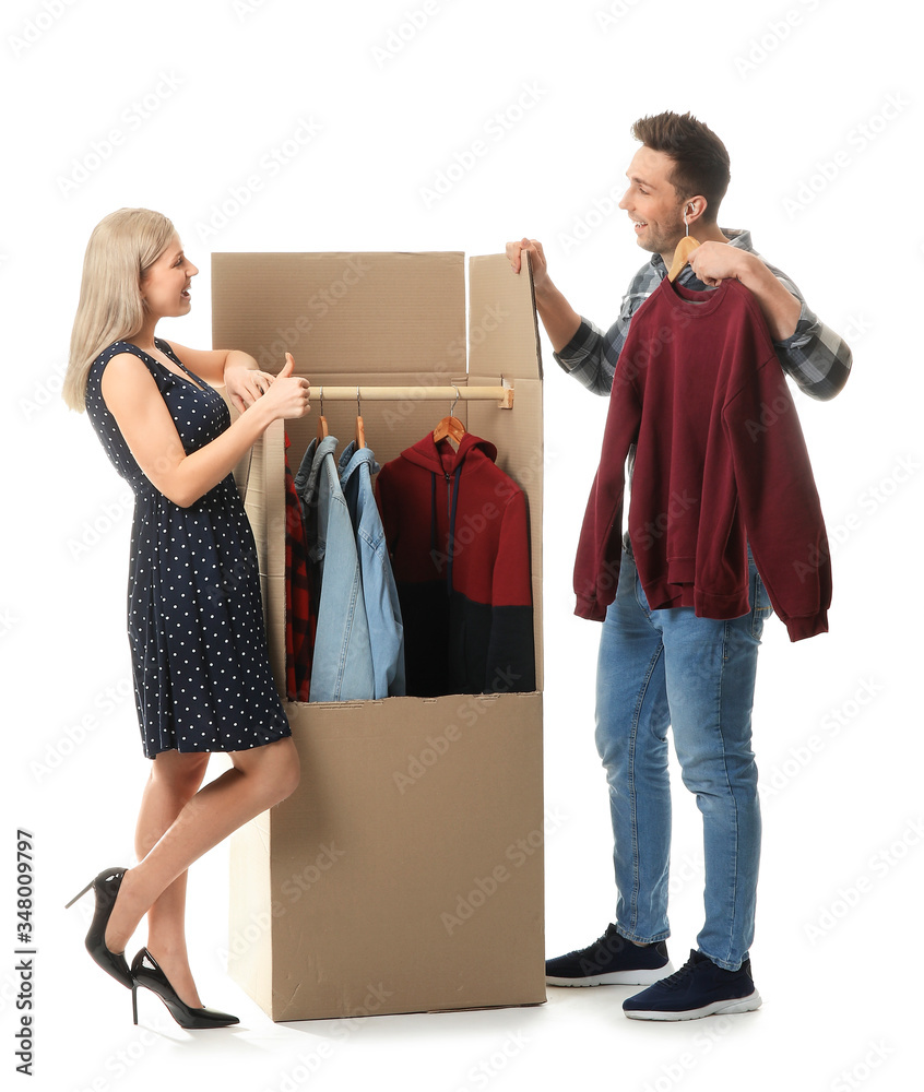 Young couple unpacking clothes on white background