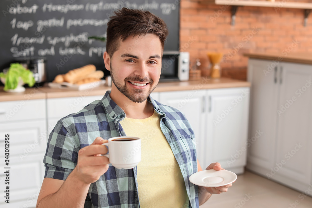 Young man drinking hot coffee in kitchen