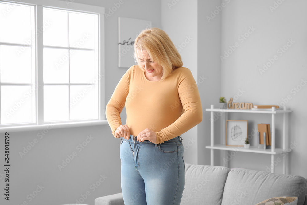 Troubled overweight woman in tight clothes at home